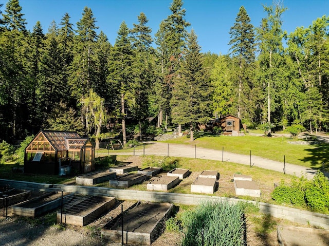 151 Handkerchief Creek Dr, Kalispell, MT 59901 - view of green lawn with a garden, a greenhouse, a view of trees, and an outbuilding