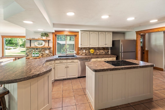 151 Handkerchief Creek Dr, Kalispell, MT 59901 - kitchen featuring appliances with stainless steel finishes, decorative backsplash, a peninsula, dark countertops, and a kitchen island