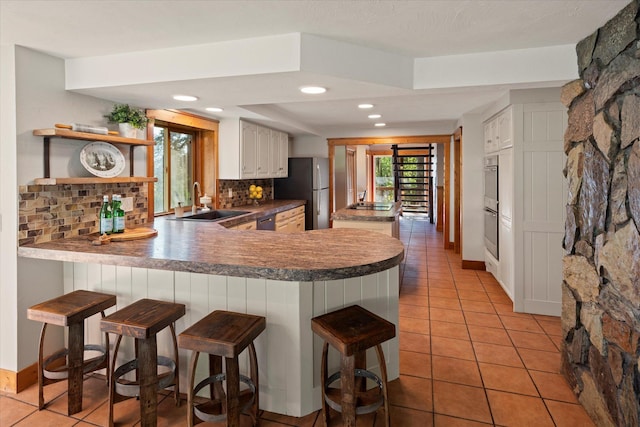 151 Handkerchief Creek Dr, Kalispell, MT 59901 - kitchen with stainless steel appliances, light tile patterned flooring, tasteful backsplash, a peninsula, and a breakfast bar