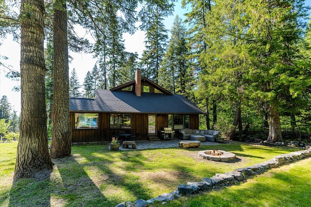 151 Handkerchief Creek Dr, Kalispell, MT 59901 - back of house with a chimney, a yard, a shingled roof, an outdoor living space with a fire pit, and a patio area
