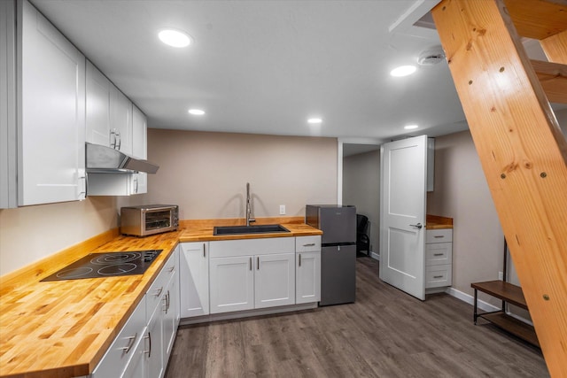 151 Handkerchief Creek Dr, Kalispell, MT 59901 - kitchen with wooden counters, black electric cooktop, under cabinet range hood, freestanding refrigerator, and dark wood-style flooring
