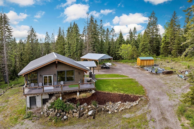 4111 Foothill Rd, Kalispell, MT 59901 - view of front of house featuring a view of trees, a wooden deck, a detached carport, and driveway
