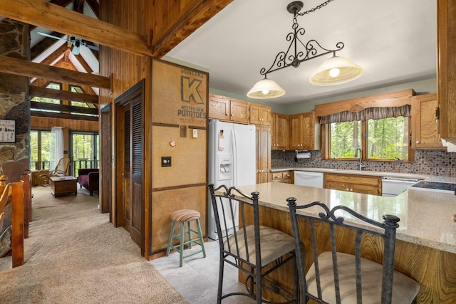 250 Sunday Ln, Kalispell, MT 59901 - kitchen featuring white appliances, tasteful backsplash, a peninsula, light stone counters, and hanging light fixtures