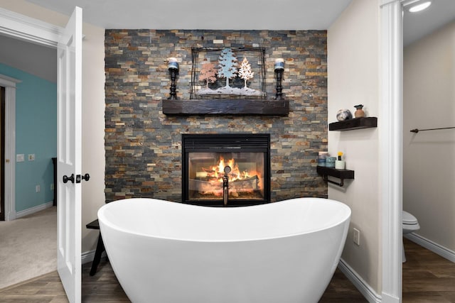 360 Plantation Dr, Kalispell, MT 59901 - full bathroom with a soaking tub, toilet, wood finished floors, and baseboards