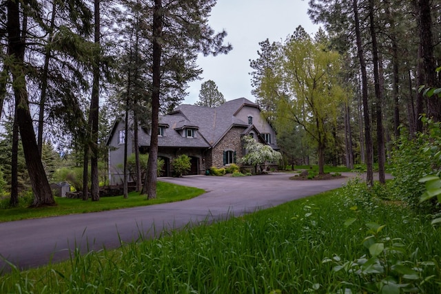 360 Plantation Dr, Kalispell, MT 59901 - french country inspired facade with stone siding, curved driveway, stucco siding, and a garage
