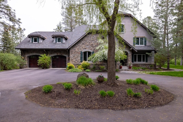 360 Plantation Dr, Kalispell, MT 59901 - view of front of house with stone siding, curved driveway, a garage, and stucco siding
