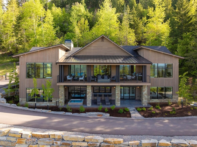 175 N Prairiesmoke Cir, Whitefish, MT 59937 - rear view of house featuring a patio, a chimney, metal roof, and stone siding