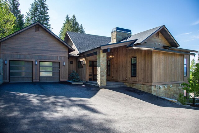 175 N Prairiesmoke Cir, Whitefish, MT 59937 - chalet / cabin featuring a chimney, a shingled roof, a garage, a porch, and driveway