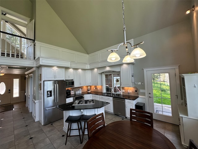 2413 Capstone Ct, Thompson Falls, MT 59873 - kitchen featuring stainless steel appliances, dark countertops, high vaulted ceiling, light tile patterned flooring, and white cabinetry