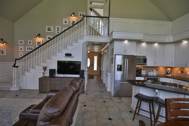 2413 Capstone Ct, Thompson Falls, MT 59873 - kitchen with stainless steel appliances, high vaulted ceiling, dark countertops, a decorative wall, and a kitchen bar