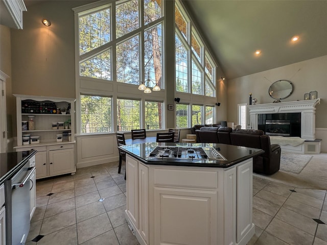 2413 Capstone Ct, Thompson Falls, MT 59873 - kitchen with high vaulted ceiling, dark countertops, light tile patterned flooring, white cabinetry, and a premium fireplace