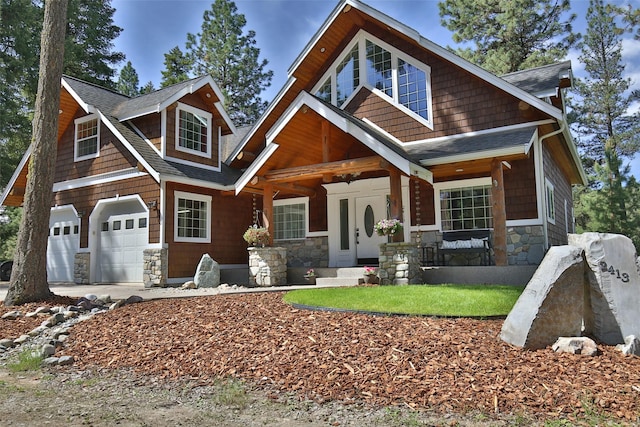 2413 Capstone Ct, Thompson Falls, MT 59873 - craftsman-style home featuring stone siding, covered porch, roof with shingles, concrete driveway, and an attached garage