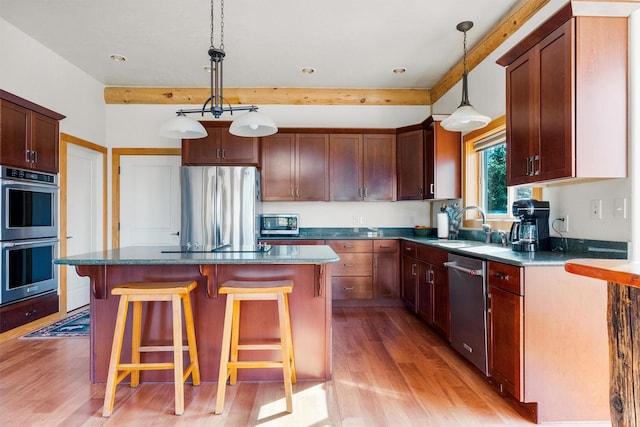 956 Falling Star Rd, Victor, MT 59875 - kitchen featuring stainless steel appliances, light wood finished floors, a kitchen bar, a center island, and hanging light fixtures