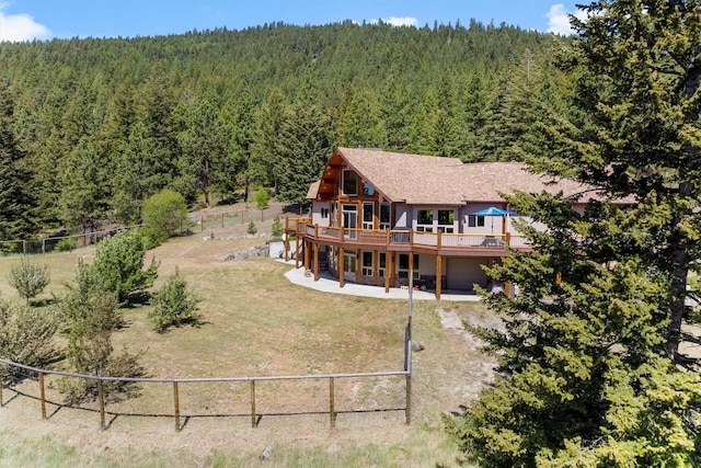 956 Falling Star Rd, Victor, MT 59875 - back of house with a view of trees, a deck, a fenced backyard, and an attached garage