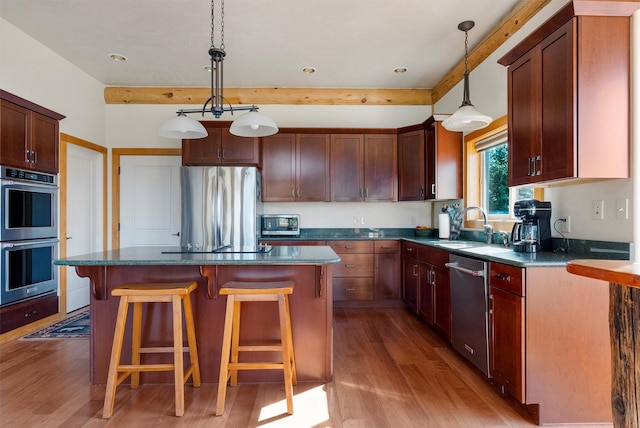956 Falling Star Rd, Victor, MT 59875 - kitchen with appliances with stainless steel finishes, wood finished floors, a kitchen bar, a kitchen island, and hanging light fixtures