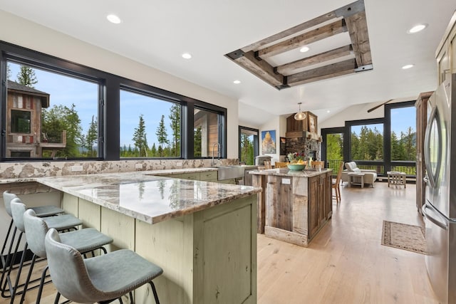 103 Glacier Hills Dr E, Martin City, MT 59926 - kitchen featuring recessed lighting, freestanding refrigerator, a kitchen breakfast bar, light wood-style floors, and light stone counters