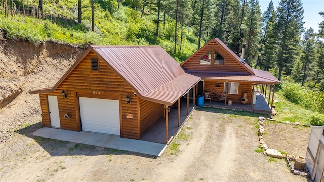 18711 Copper Ridge Trl, Florence, MT 59833 - log home featuring driveway, a porch, metal roof, and a view of trees