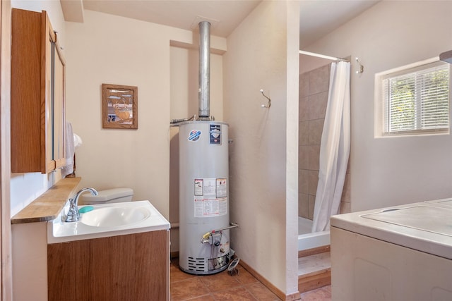 18711 Copper Ridge Trl, Florence, MT 59833 - bathroom with gas water heater, vanity, washer / dryer, a tile shower, and tile patterned floors