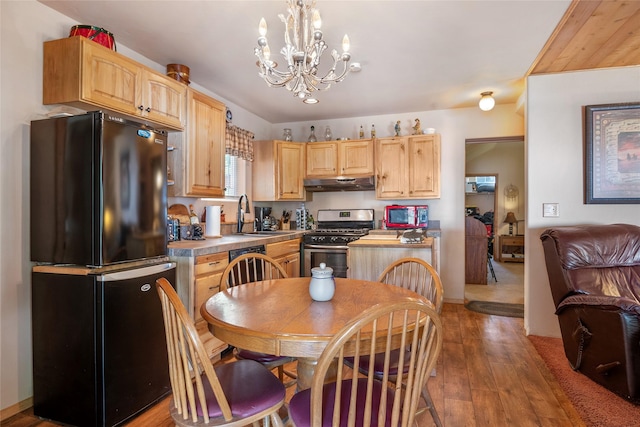 18711 Copper Ridge Trl, Florence, MT 59833 - kitchen with stainless steel range with gas stovetop, freestanding refrigerator, under cabinet range hood, light brown cabinets, and a sink