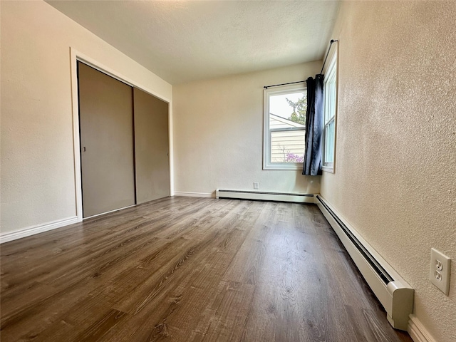 2513 8th Ave N, Great Falls, MT 59401 - unfurnished bedroom featuring a textured wall, baseboard heating, wood finished floors, and baseboards