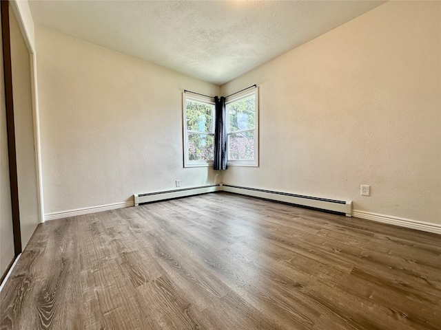 2513 8th Ave N, Great Falls, MT 59401 - unfurnished room featuring wood finished floors, baseboards, a textured ceiling, baseboard heating, and a textured wall