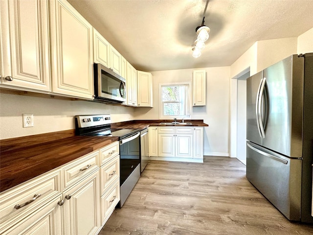2513 8th Ave N, Great Falls, MT 59401 - kitchen featuring appliances with stainless steel finishes, wood counters, a sink, and light wood finished floors