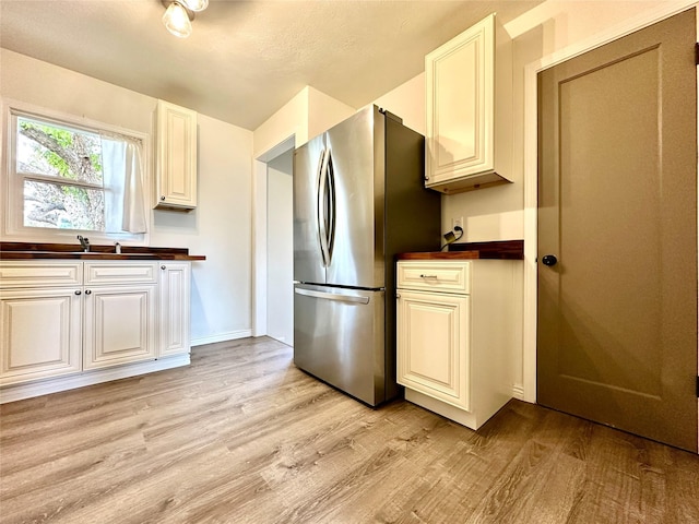2513 8th Ave N, Great Falls, MT 59401 - kitchen featuring freestanding refrigerator, light wood finished floors, butcher block counters, a sink, and white cabinetry