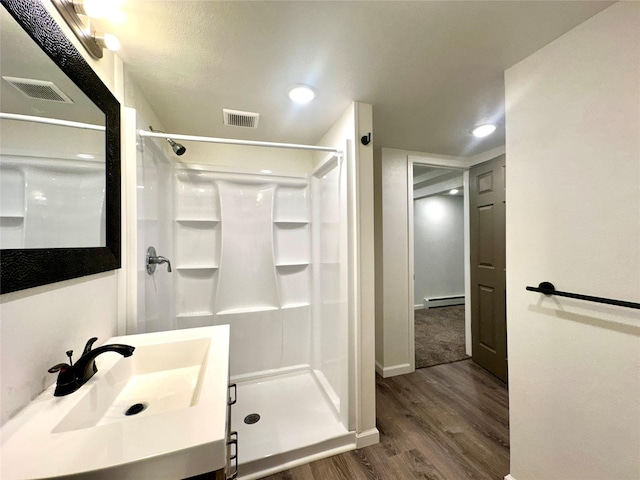 2513 8th Ave N, Great Falls, MT 59401 - full bathroom featuring baseboard heating, wood finished floors, a sink, a stall shower, and recessed lighting