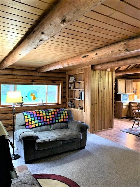 7191 Boy Scout Rd, Seeley Lake, MT 59868 - living room featuring a wooden ceiling with exposed beams, light wood-style floors, log walls, and wooden walls