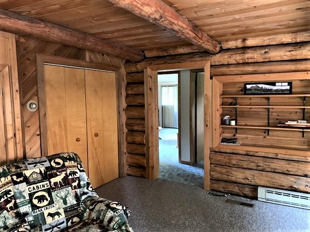 7191 Boy Scout Rd, Seeley Lake, MT 59868 - carpeted bedroom featuring wood ceiling with exposed beams and rustic walls
