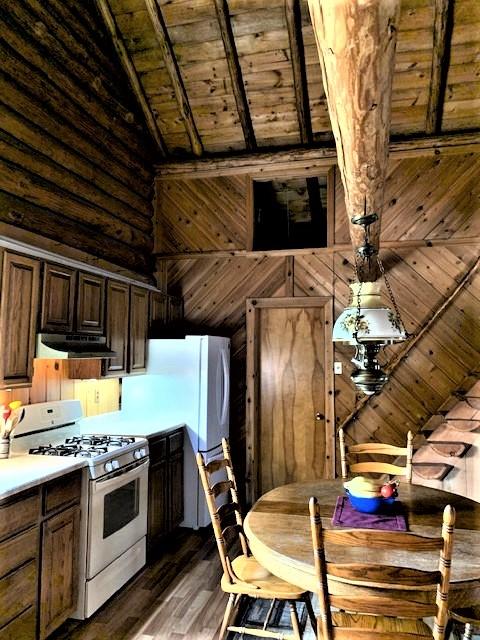 7191 Boy Scout Rd, Seeley Lake, MT 59868 - kitchen with white gas range oven, a wooden ceiling with exposed beams, under cabinet range hood, wood finished floors, and light countertops