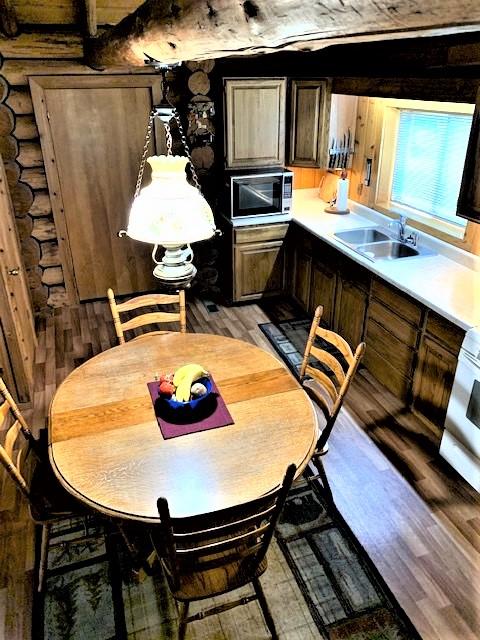 7191 Boy Scout Rd, Seeley Lake, MT 59868 - kitchen featuring light wood-style floors, light countertops, a sink, and log walls