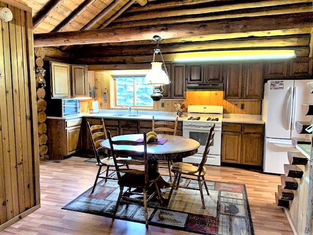 7191 Boy Scout Rd, Seeley Lake, MT 59868 - kitchen with white appliances, light wood-type flooring, a sink, wooden ceiling, and under cabinet range hood