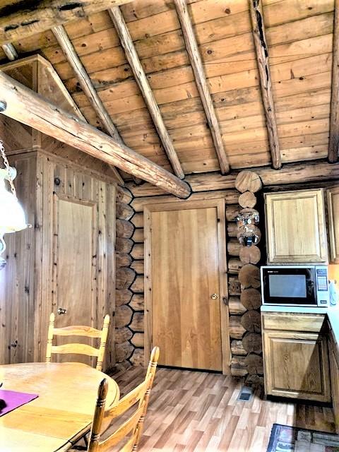 7191 Boy Scout Rd, Seeley Lake, MT 59868 - dining area with wood ceiling, log walls, and light wood-style flooring