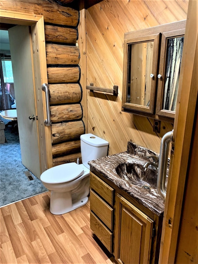 7191 Boy Scout Rd, Seeley Lake, MT 59868 - bathroom with rustic walls, vanity, toilet, and wood finished floors