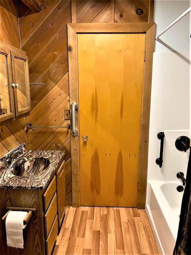 7191 Boy Scout Rd, Seeley Lake, MT 59868 - full bath featuring vanity, wood finished floors, bathing tub / shower combination, and wooden walls
