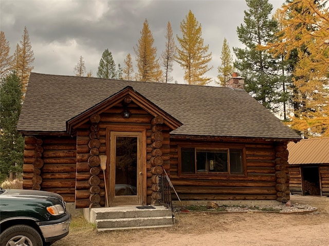 7191 Boy Scout Rd, Seeley Lake, MT 59868 - cabin featuring log exterior, roof with shingles, and a chimney