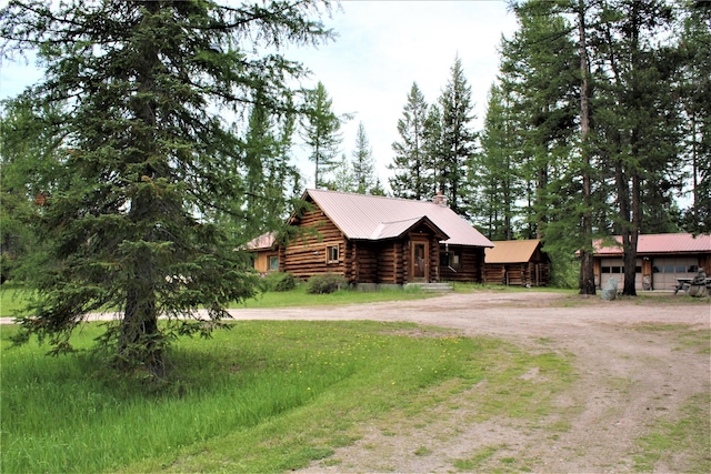 7191 Boy Scout Rd, Seeley Lake, MT 59868 - cabin featuring driveway, log exterior, a chimney, and metal roof