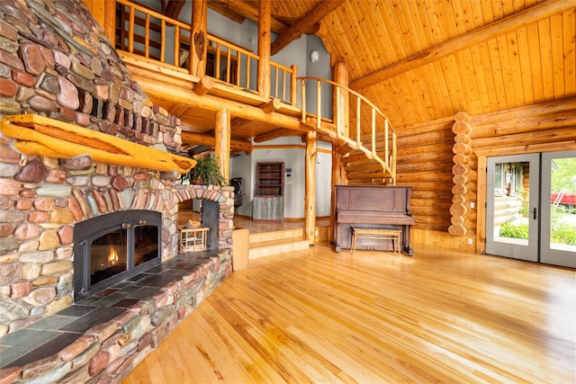 1473 Foothill Rd, Kalispell, MT 59901 - unfurnished living room featuring rustic walls, high vaulted ceiling, a wooden ceiling with exposed beams, wood finished floors, and a stone fireplace