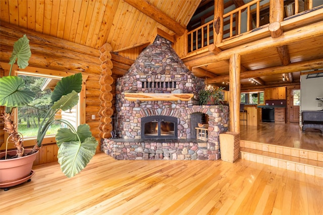1473 Foothill Rd, Kalispell, MT 59901 - unfurnished living room featuring a wood ceiling with exposed beams, healthy amount of natural light, rustic walls, wood finished floors, and a fireplace