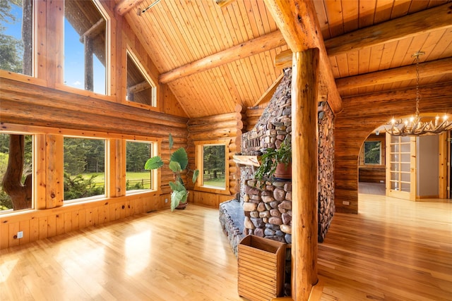 1473 Foothill Rd, Kalispell, MT 59901 - unfurnished living room featuring log walls, a chandelier, a wooden ceiling with exposed beams, healthy amount of natural light, and hardwood / wood-style flooring