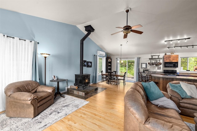 1473 Foothill Rd, Kalispell, MT 59901 - living area with a wood stove, ceiling fan, an AC wall unit, lofted ceiling, and light wood finished floors