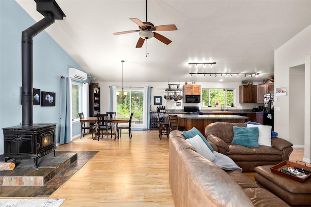 1473 Foothill Rd, Kalispell, MT 59901 - living room with a wall mounted AC, a wood stove, light wood-type flooring, a ceiling fan, and vaulted ceiling