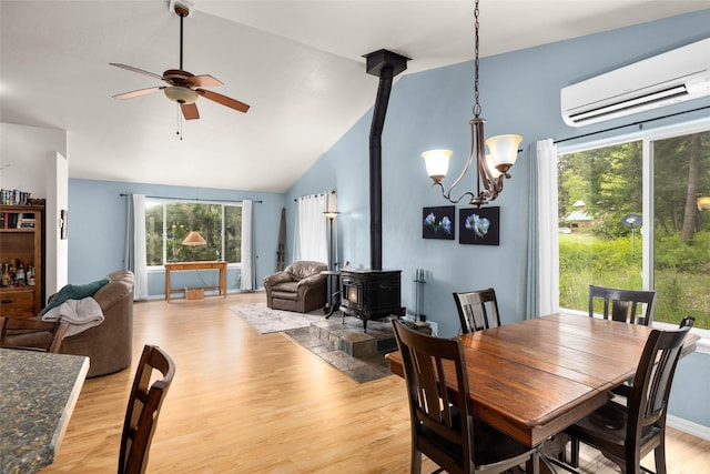 1473 Foothill Rd, Kalispell, MT 59901 - dining area with a wood stove, an AC wall unit, a ceiling fan, light wood-type flooring, and vaulted ceiling