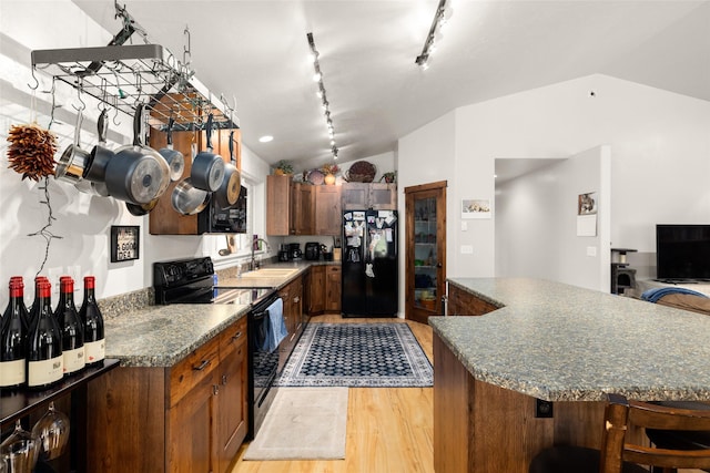 1473 Foothill Rd, Kalispell, MT 59901 - kitchen with black appliances, vaulted ceiling, light wood finished floors, track lighting, and a center island