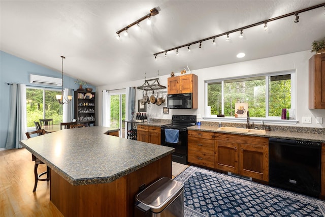1473 Foothill Rd, Kalispell, MT 59901 - kitchen with black appliances, dark countertops, vaulted ceiling, brown cabinetry, and a wall mounted air conditioner