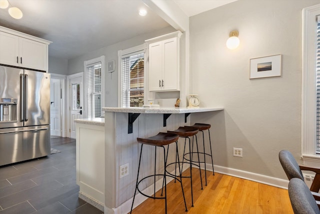 322 W Lawrence St, Helena, MT 59601 - kitchen featuring stainless steel refrigerator with ice dispenser, a kitchen breakfast bar, white cabinetry, baseboards, and dark wood-style floors