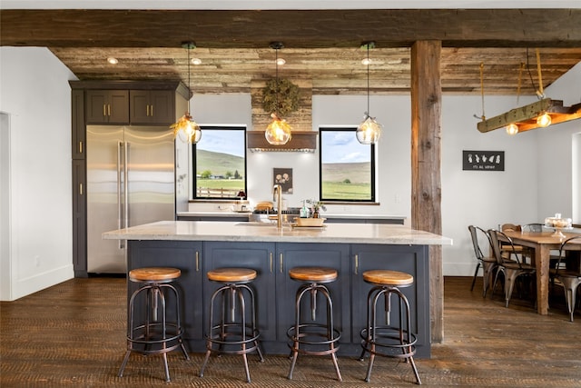 42730 Ridgeway Rd, Charlo, MT 59824 - kitchen with stainless steel built in fridge, dark wood finished floors, light stone countertops, an island with sink, and beamed ceiling