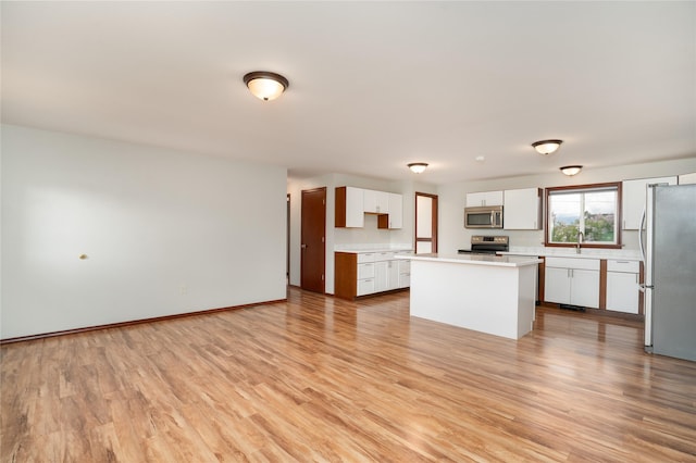413 S Oak St, Townsend, MT 59644 - kitchen featuring appliances with stainless steel finishes, white cabinetry, light countertops, light wood-style flooring, and a center island