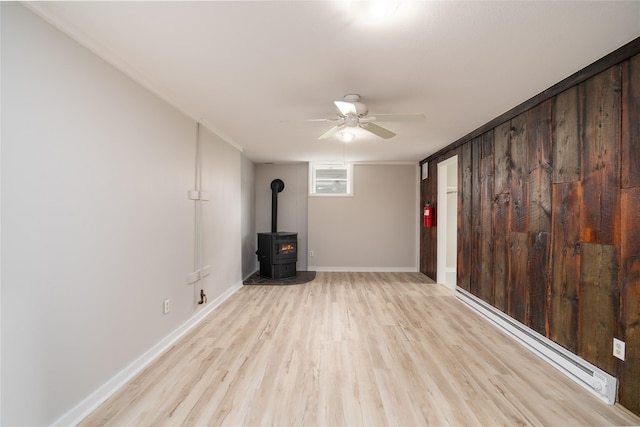 413 S Oak St, Townsend, MT 59644 - unfurnished living room featuring ceiling fan, light wood-type flooring, a wood stove, baseboard heating, and baseboards
